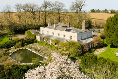 An aerial view of a period country house and gardens, the kind of property By Design Homes sells across North Devon and Exmoor