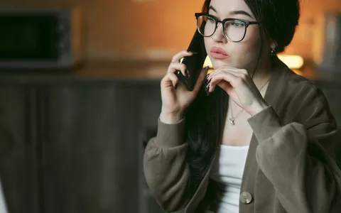 A professional taking a phone call in a warmly lit room in the evening