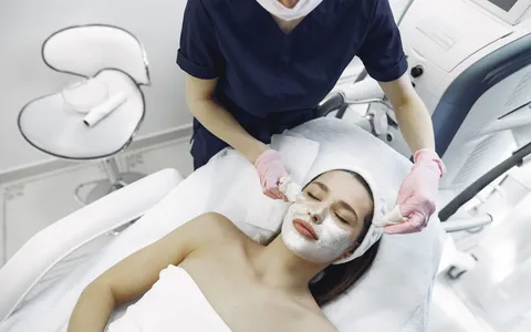 An aesthetic practitioner applying a facial treatment to a client in a modern skincare clinic