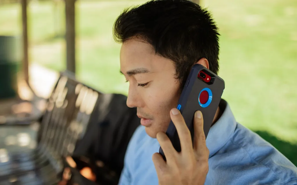 A man in a blue shirt taking a call on a mobile phone