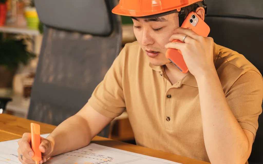 Heating engineer in a hard hat taking a call on a mobile phone
