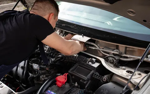 Mechanic leaning under an open bonnet working on a car engine
